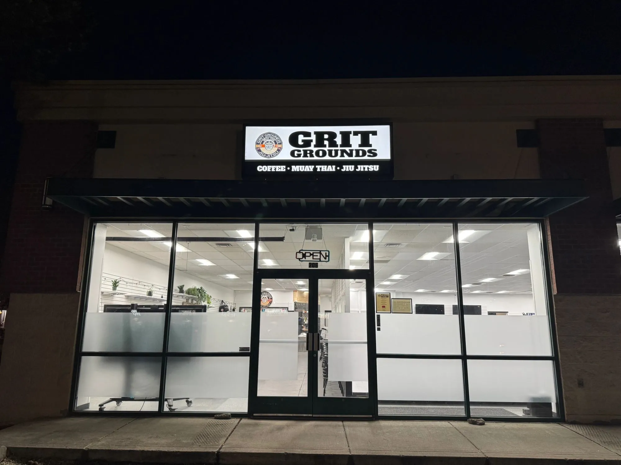 The storefront at night with the sign lit